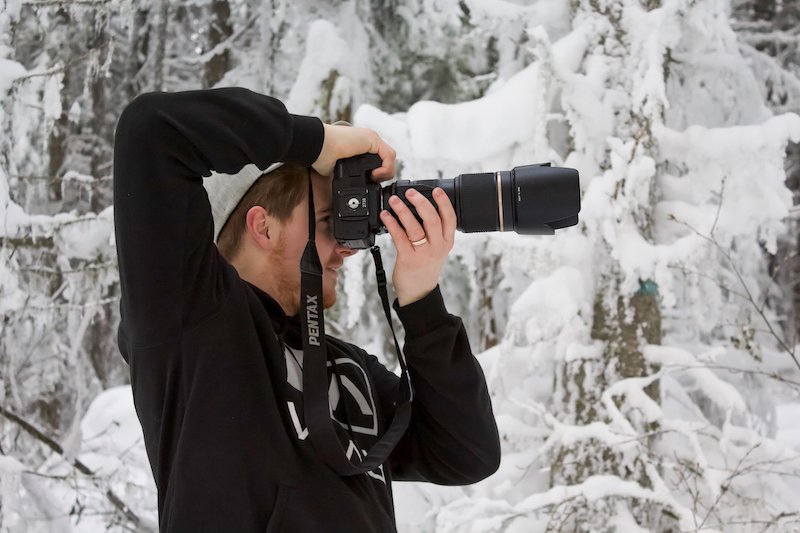 Hiilite | Marketing, SEO, Branding, Web & Graphic Design A photographer adjusting his camera settings for an outdoor photoshoot in the snow