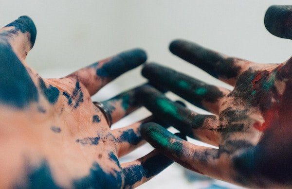 A pair of hands covered in paint reaching out